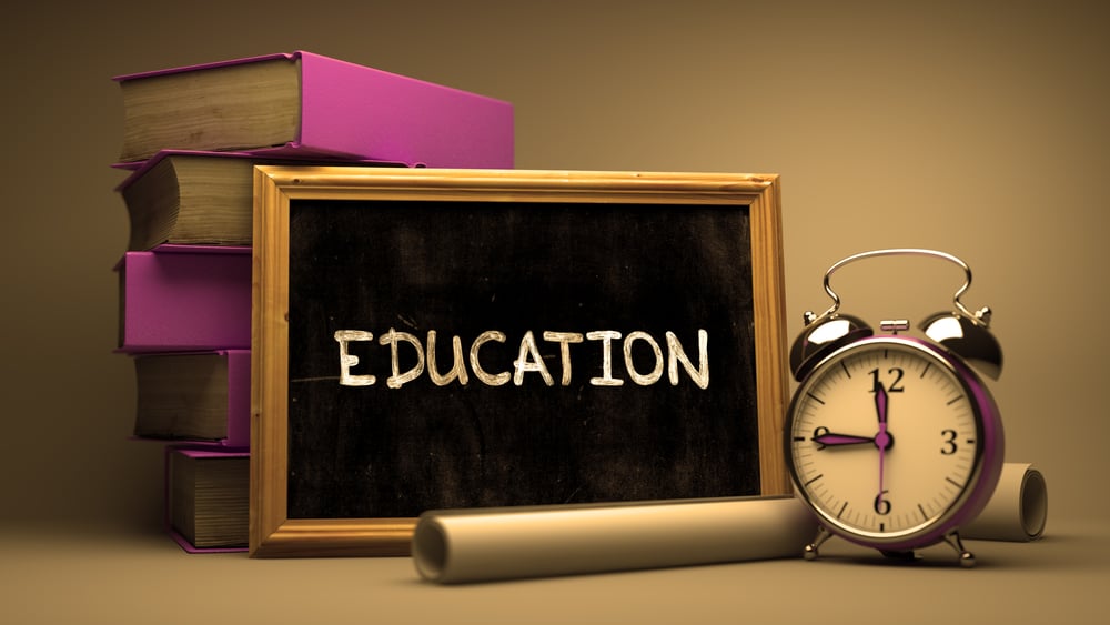 Handwritten Education on a Chalkboard. Composition with Chalkboard and Stack of Books, Alarm Clock and Rolls of Paper on Blurred Background. Toned Image.-1